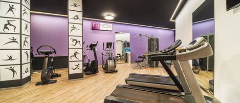 A gym with treadmills, elliptical machines, and a wall with fitness icons.