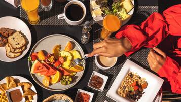 Un desayuno con una variedad de platillos, como waffles, fruta y café.
