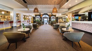 A spacious lobby with a central seating area, a reception desk, and a bar on the left. - Hôtel Exsel Créolia  (Saint-Denis)