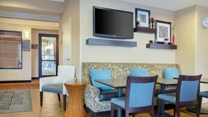 A hotel lobby with seating, a TV, and a reception desk.