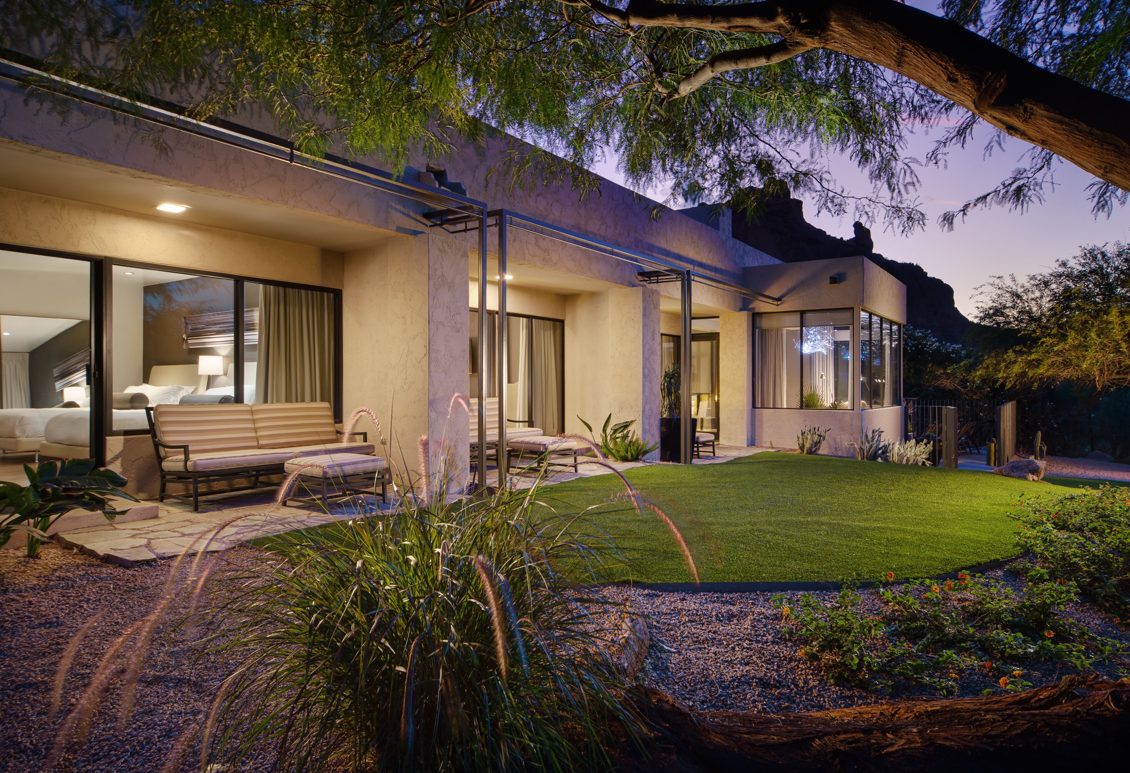 A modern house with a patio, outdoor seating, and a well-maintained lawn.