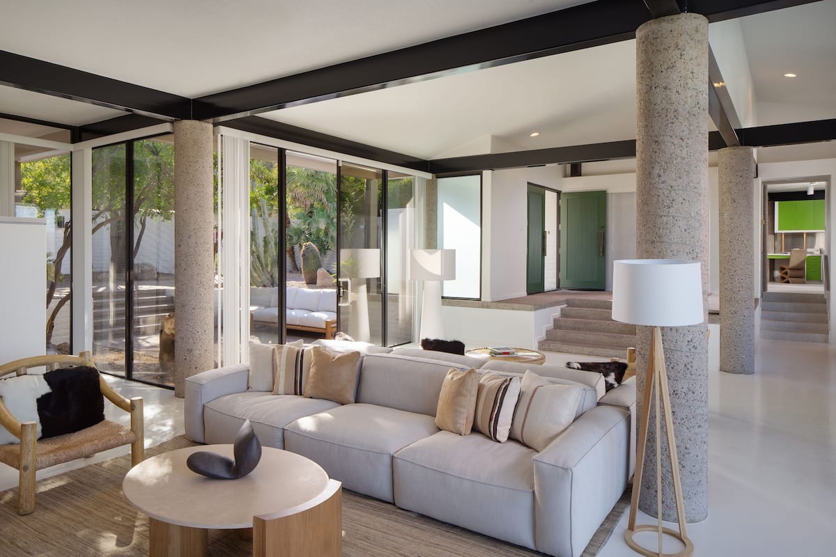 A modern living room with a large sectional sofa, a round wooden coffee table, and a floor lamp.