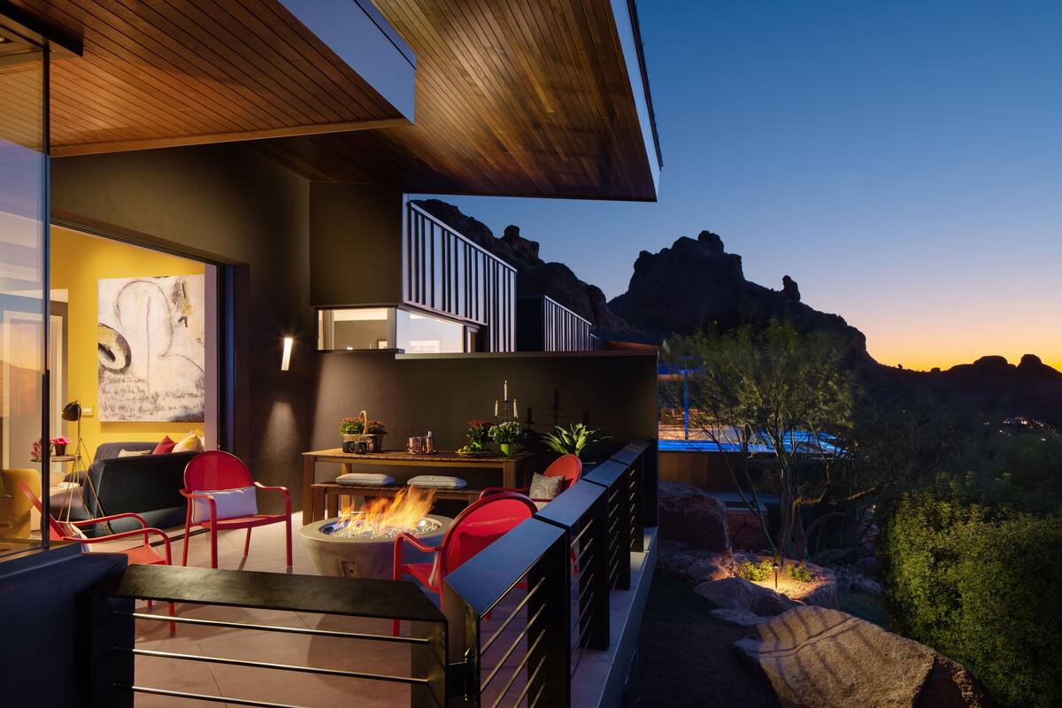 A modern outdoor living area with a fire feature, seating, and a view of the surrounding landscape.