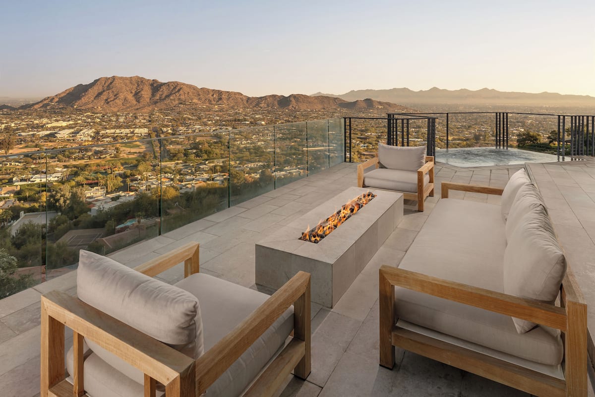 A rooftop terrace with outdoor seating, a fire feature, and a city view.