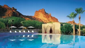 A swimming pool with clear blue water, surrounded by lounge chairs and umbrellas, with a mountain in the background. - Sanctuary Camelback Mountain Resort and Spa (Paradise Valley)