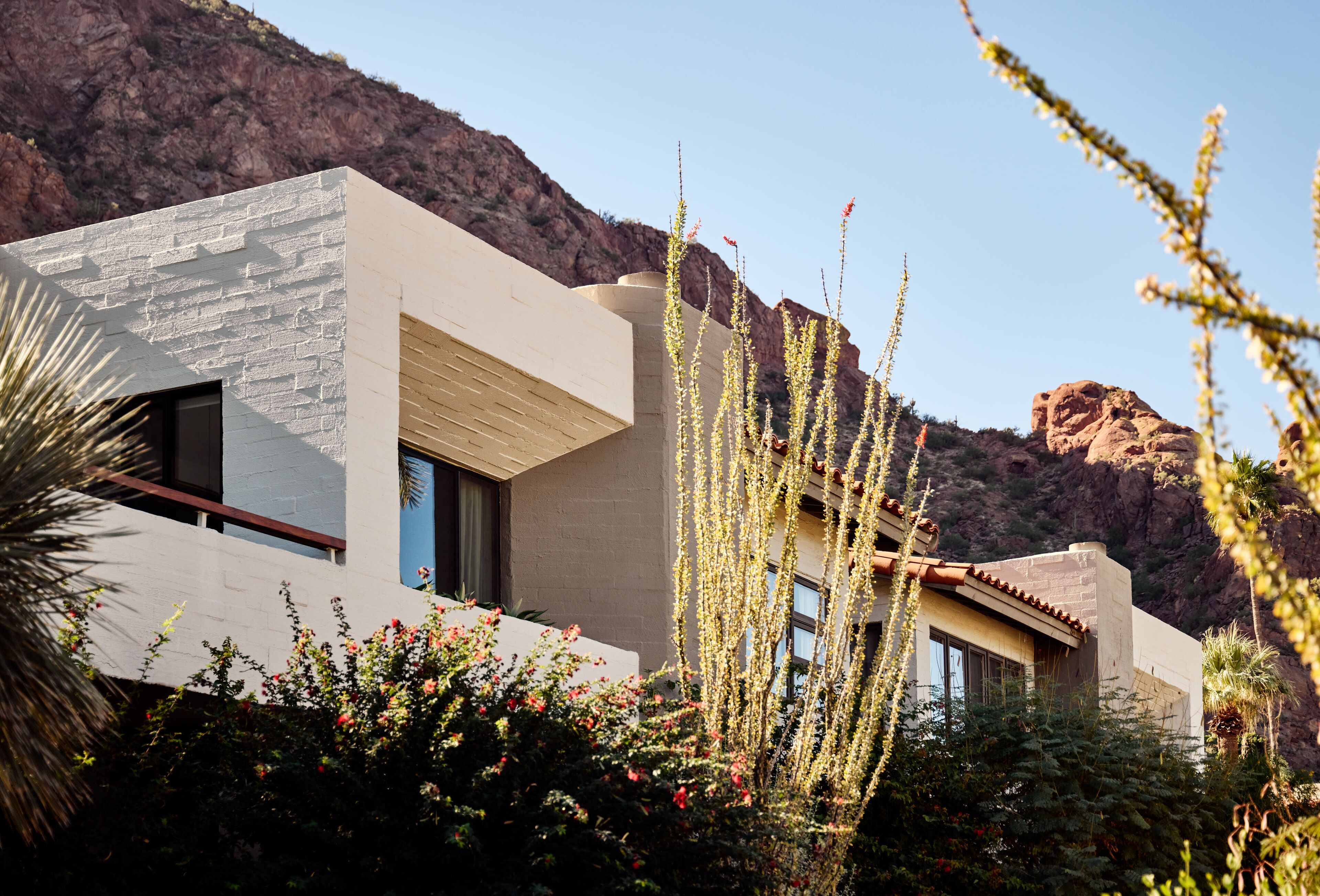 A modern building with a stone facade, large windows, and a view of a rocky mountain.