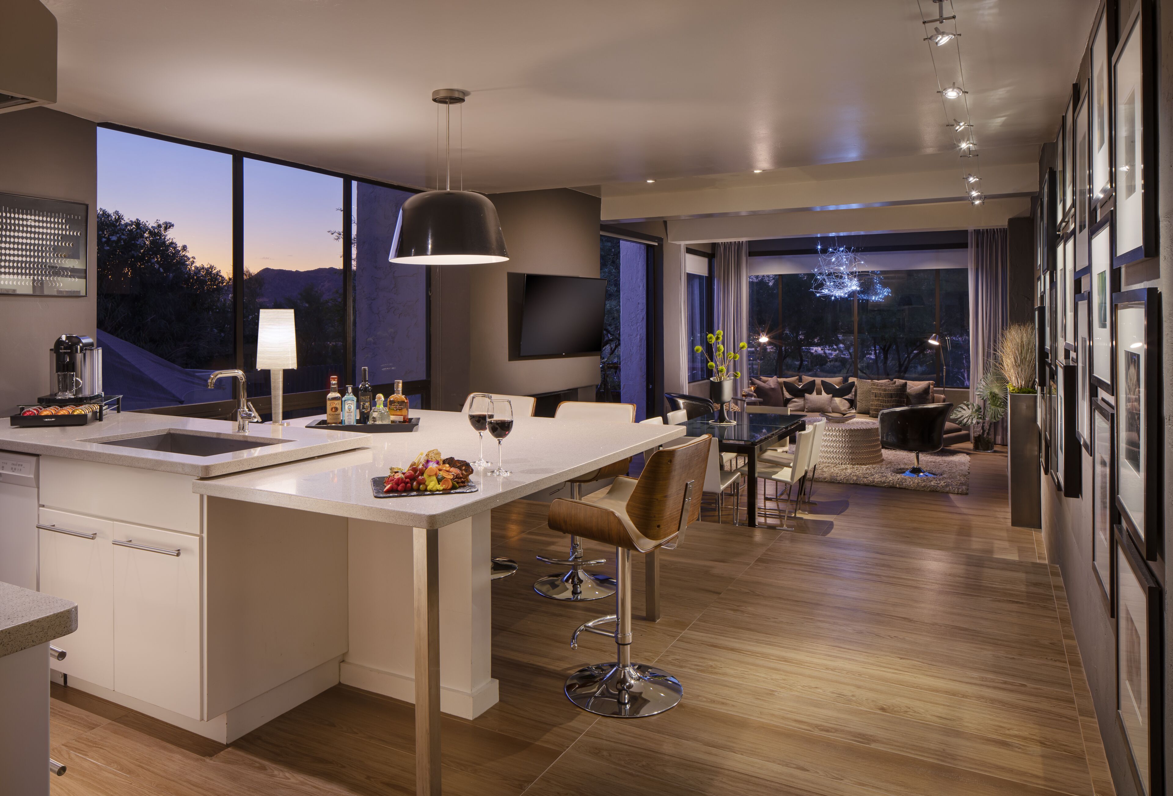 A modern kitchen with a large island, bar stools, and a dining area with a view of the outdoors.