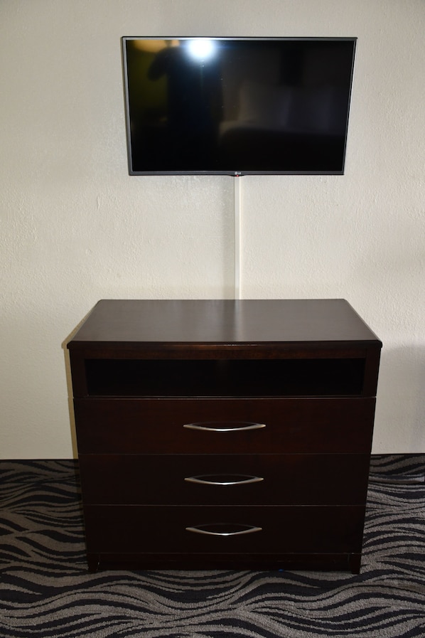 Un aparador de madera oscura con tres cajones y un televisor de pantalla plana montado encima.