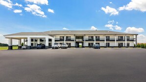 A multi-story hotel with a flat roof, a covered parking area, and a clear sky. - Americas Best Value Inn Bishopville (Bishopville)