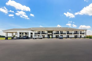 A multi-story hotel with a flat roof, a covered parking area, and a clear sky. - Americas Best Value Inn Bishopville (Bishopville)