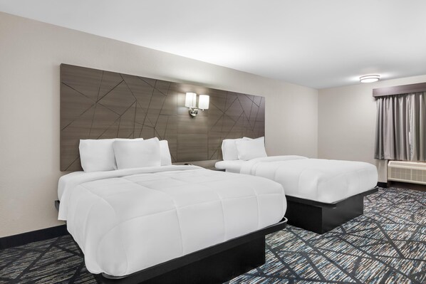 A hotel room with two beds, a large wall-mounted light fixture, and a patterned carpet.