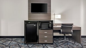 A hotel room with a desk, a flat-screen TV, a microwave, a refrigerator, a chair, and a lamp. - Americas Best Value Inn Bishopville (Bishopville)