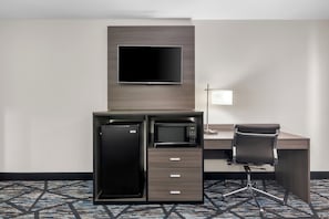 A hotel room with a desk, a flat-screen TV, a microwave, a refrigerator, a chair, and a lamp. - Americas Best Value Inn Bishopville (Bishopville)