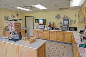 A coffee shop interior with a coffee machine, a milk dispenser, and a display of pastries.