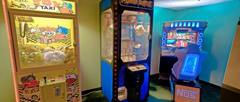 A row of arcade machines including 'TO1 TAXI' and 'Power Surge' in a room with green walls and a checkered floor.