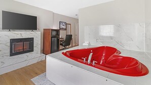 A modern bathroom with a red bathtub, a fireplace, and a flat-screen TV mounted on the wall. - Best Western Plus Brunswick Bath (Brunswick)