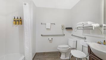 A modern bathroom with a shower, toilet, and sink, equipped with grab bars and a hand dryer.