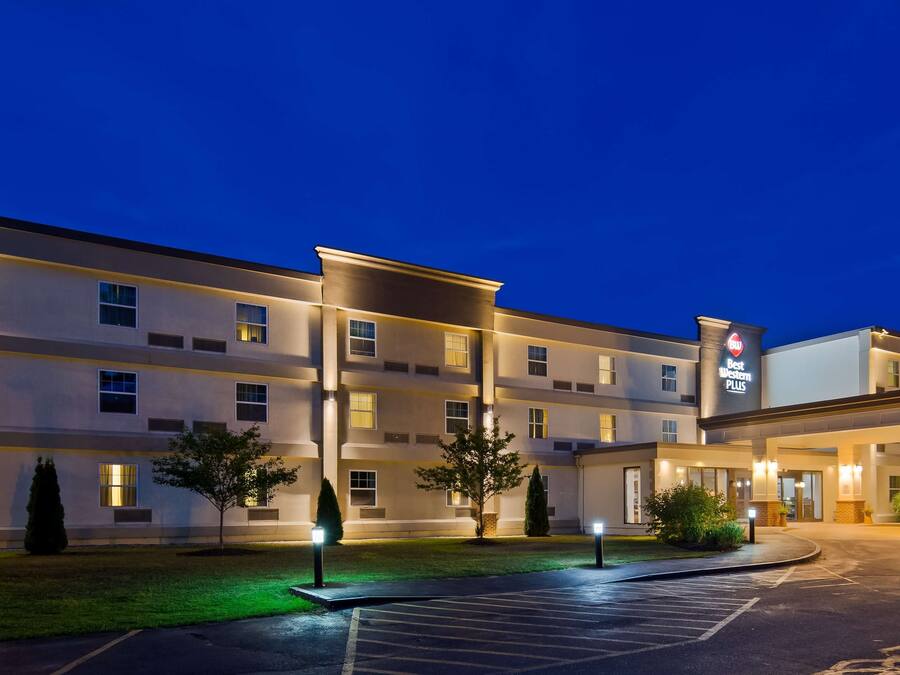 A multi-story hotel with a modern design, featuring a covered entrance and a parking lot.