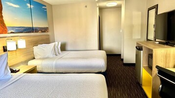 Una habitación de hotel con dos camas, un escritorio con televisor y un cuadro en la pared.