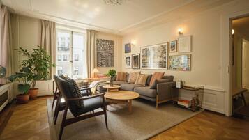 Een moderne woonkamer met een bank, fauteuils, een salontafel en een boekenkast.