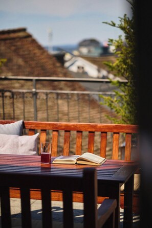 A wooden bench with a book and a glass of red beverage.