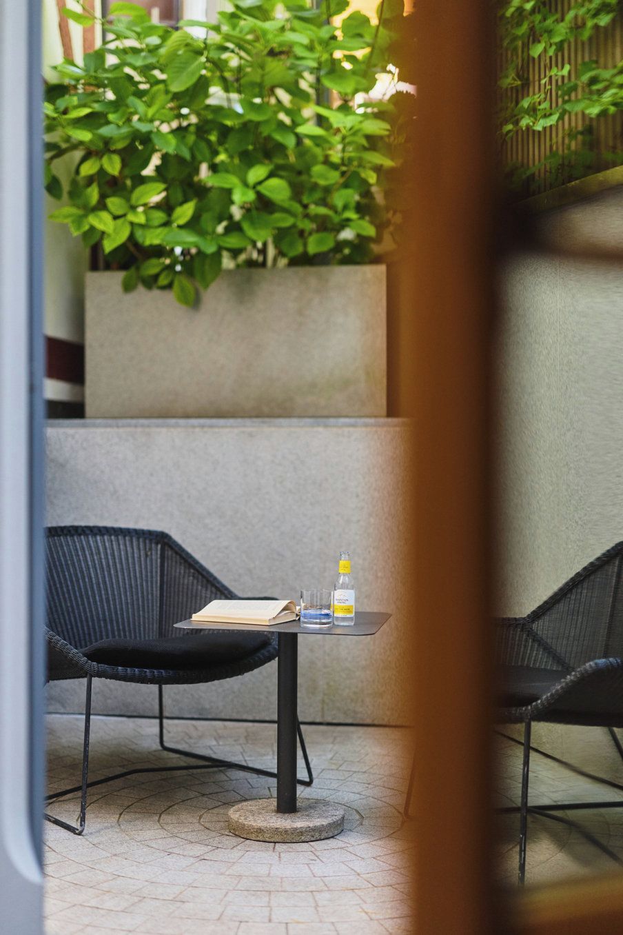 An outdoor seating area with two black chairs and a small table, a bottle of water, and a book.