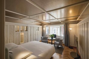 Una habitación de hotel con una cama grande, una zona de estar con dos sillones, una mesa y una lámpara de pie.