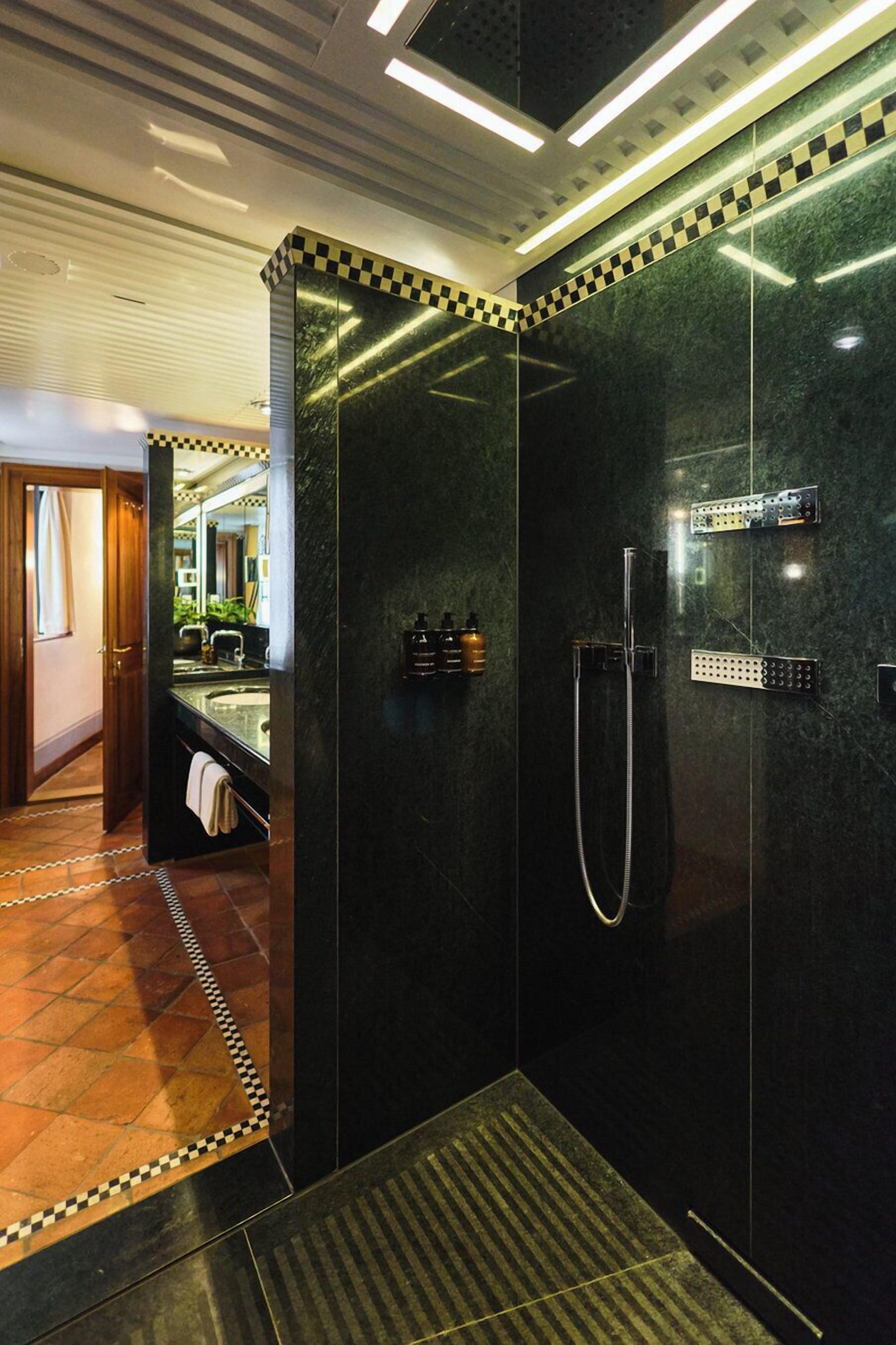 A modern bathroom with a glass-enclosed shower, a large mirror, and a checkered tile border.