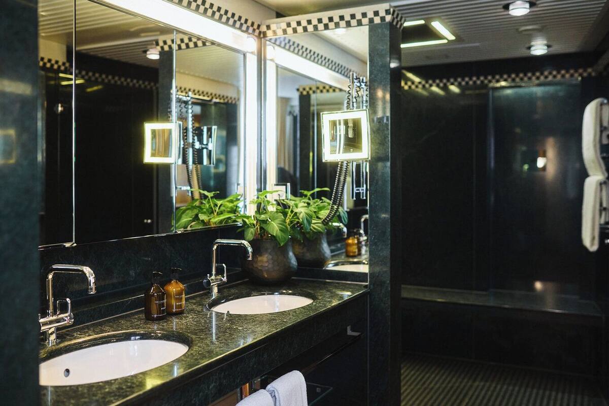 A modern bathroom with two sinks, a large mirror, and a shower area.