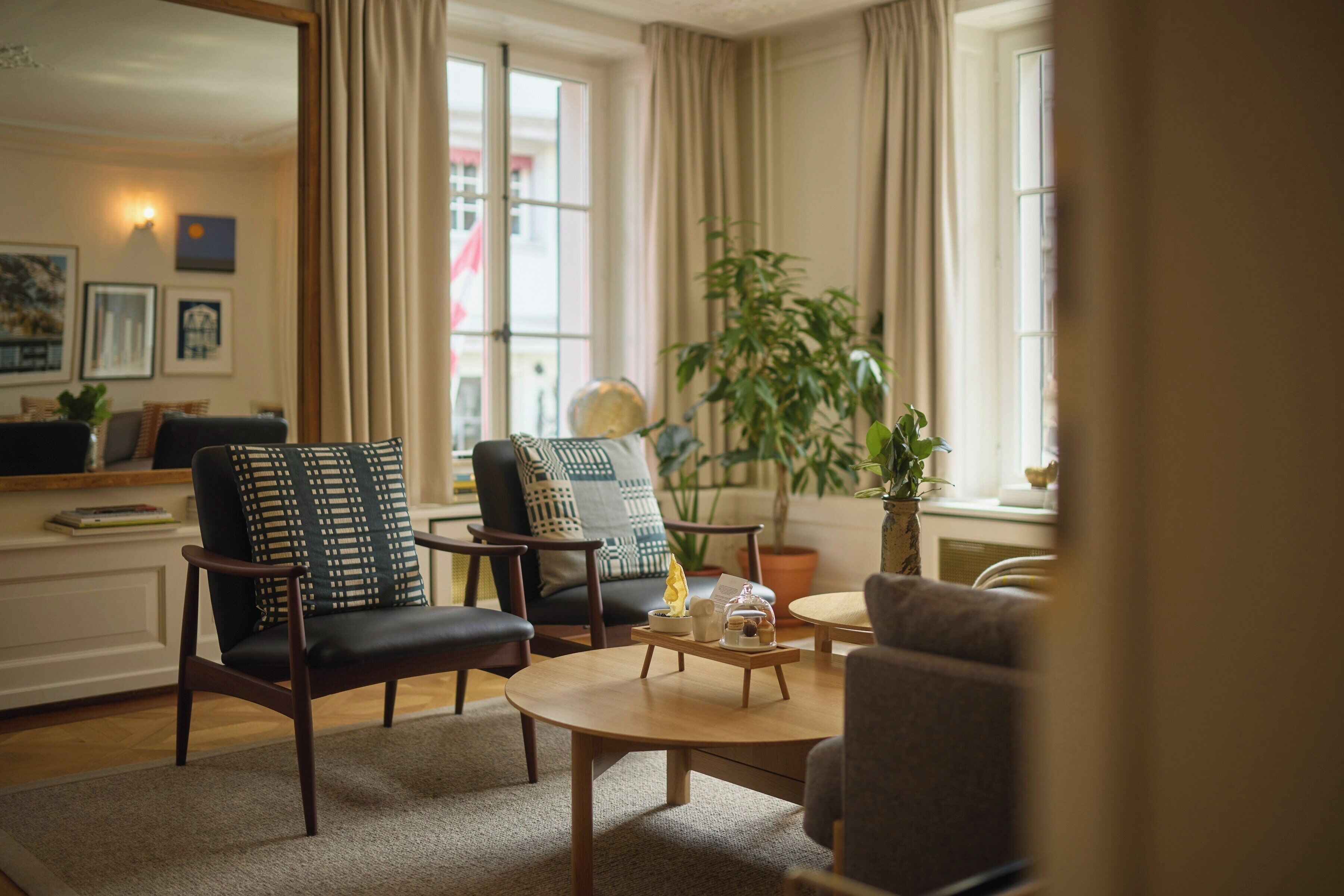 A living room with two armchairs, a coffee table, and a potted plant.
