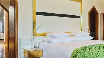 A hotel room with a bed, a bedside table with a bottle, and a green throw blanket.