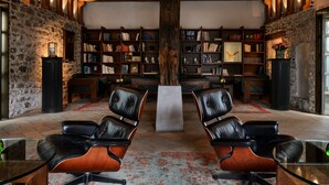A library with leather chairs, bookshelves, and a stone wall. - Widder Hotel (Zürich)