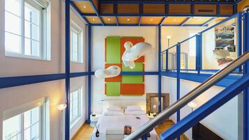 Un interior moderno con una escalera, una cama y una llamativa obra de arte en la pared.