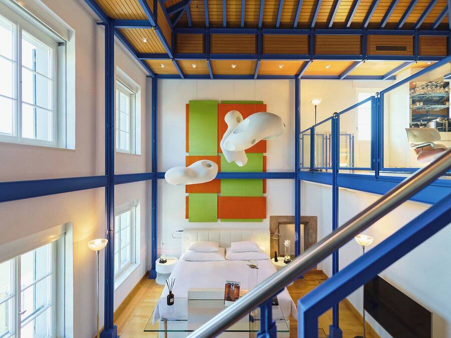 Un interior moderno con una escalera, una cama y una llamativa obra de arte en la pared.