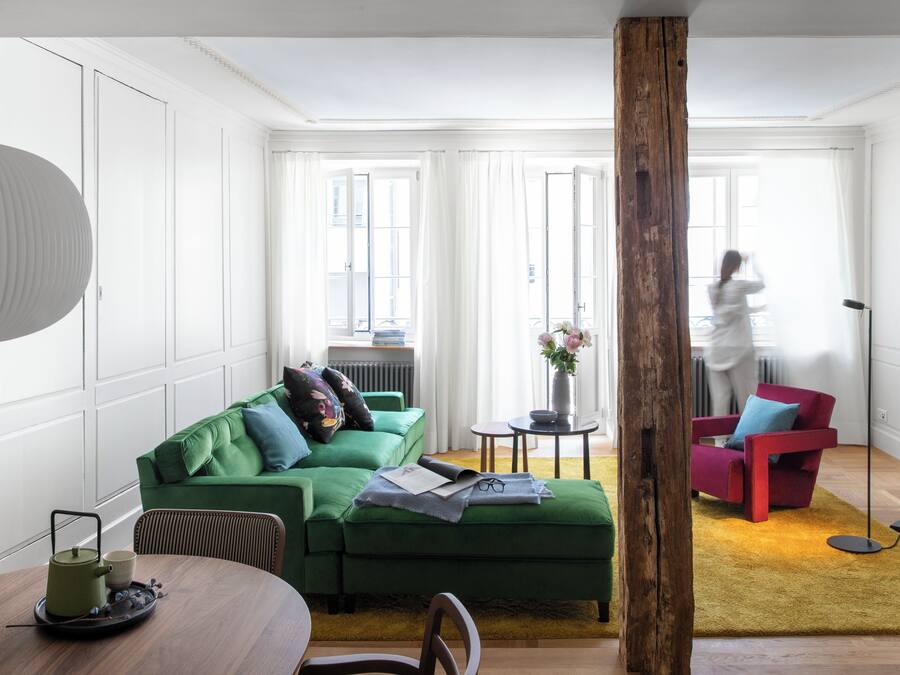 Een moderne woonkamer met een groene bank, een houten tafel en een rode stoel.