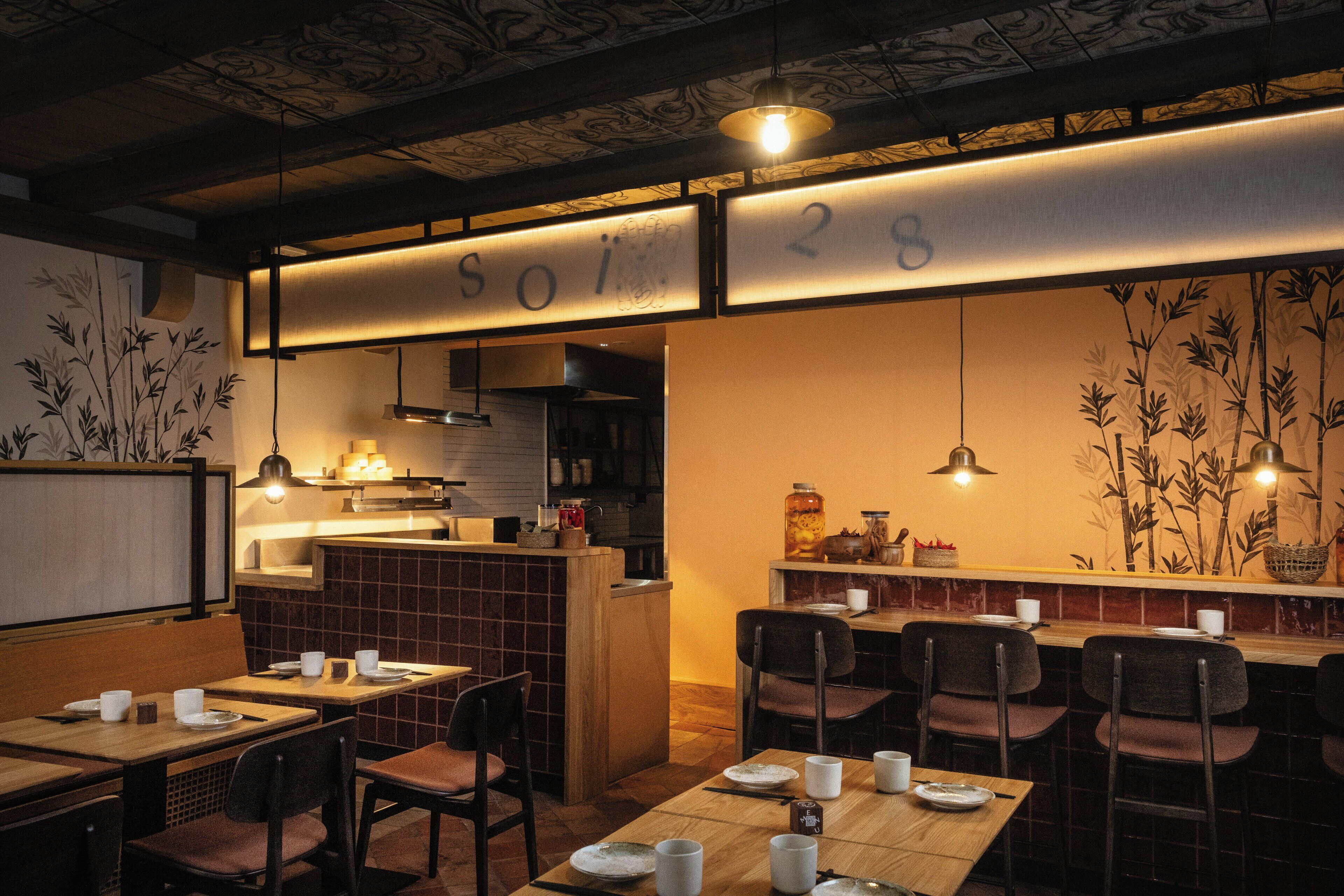 A restaurant interior with tables, chairs, a counter, and hanging lights.