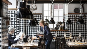 A restaurant with checkered black and white tile walls, wooden tables, and hanging pendant lights. - Widder Hotel (Zürich)