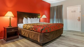 A hotel room with a large bed, two bedside lamps, a wooden nightstand, and a door.