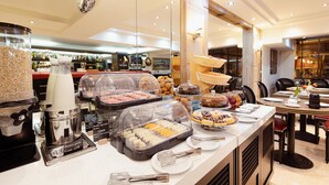 Uma área de buffet com diversos alimentos e uma máquina de café.