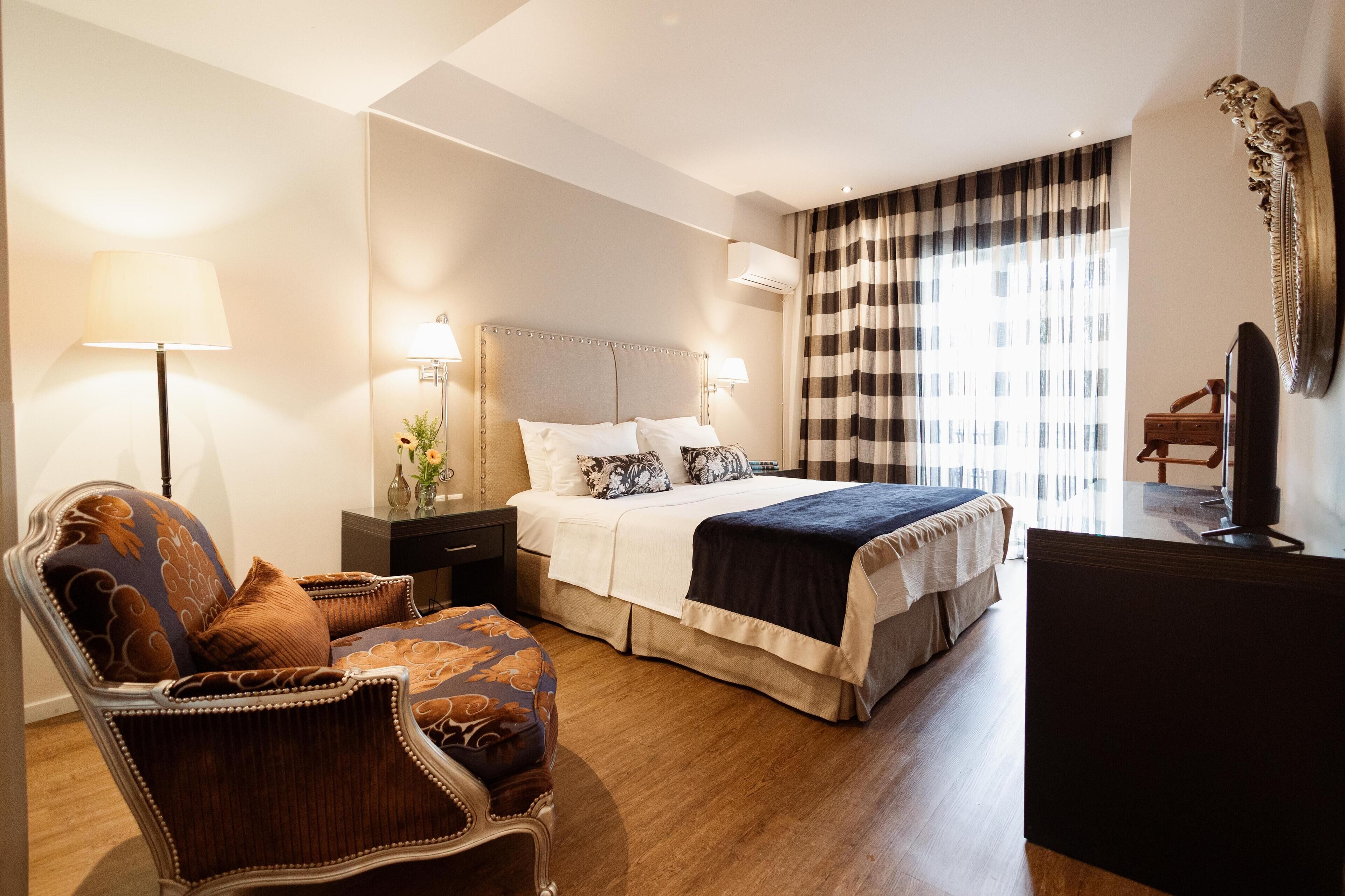 A hotel room with a bed, a chair, a desk, and a television.