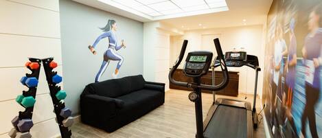 Un gimnasio en casa con cinta de correr, mancuernas y un sofá.