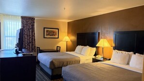 Une chambre d’hôtel avec deux lits, un bureau et une chaise. Il y a deux lampes sur les tables de chevet.