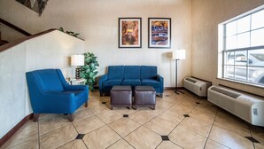 Un salon avec un canapé bleu, un fauteuil bleu, une table basse, une lampe sur pied et deux climatiseurs fixés au mur.