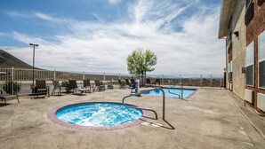 Un espace piscine sur le toit, comprenant deux piscines, des chaises longues et un arbre.
