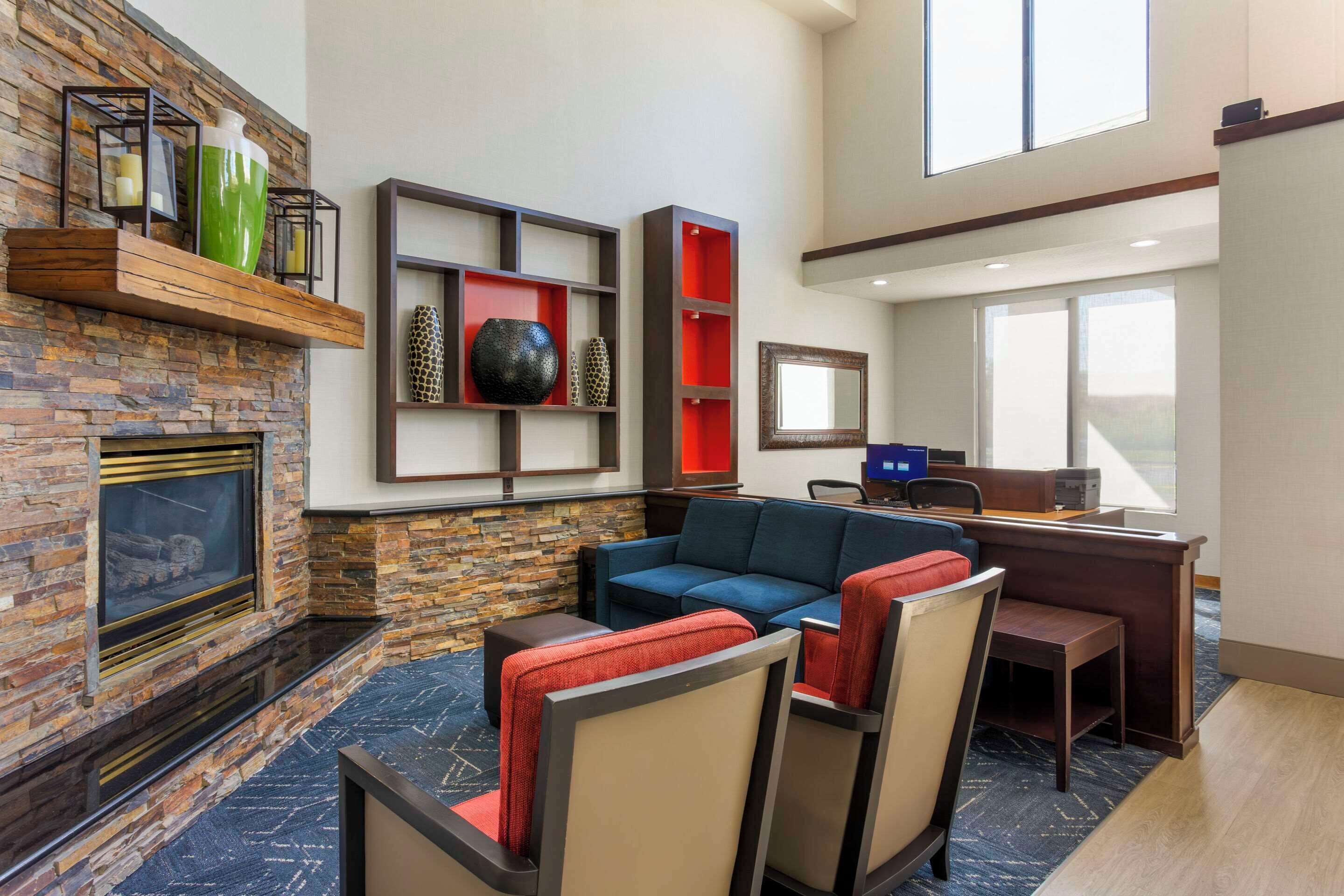 Un moderno vestíbulo de hotel con chimenea de piedra, un sofá azul y un escritorio con ordenador.
