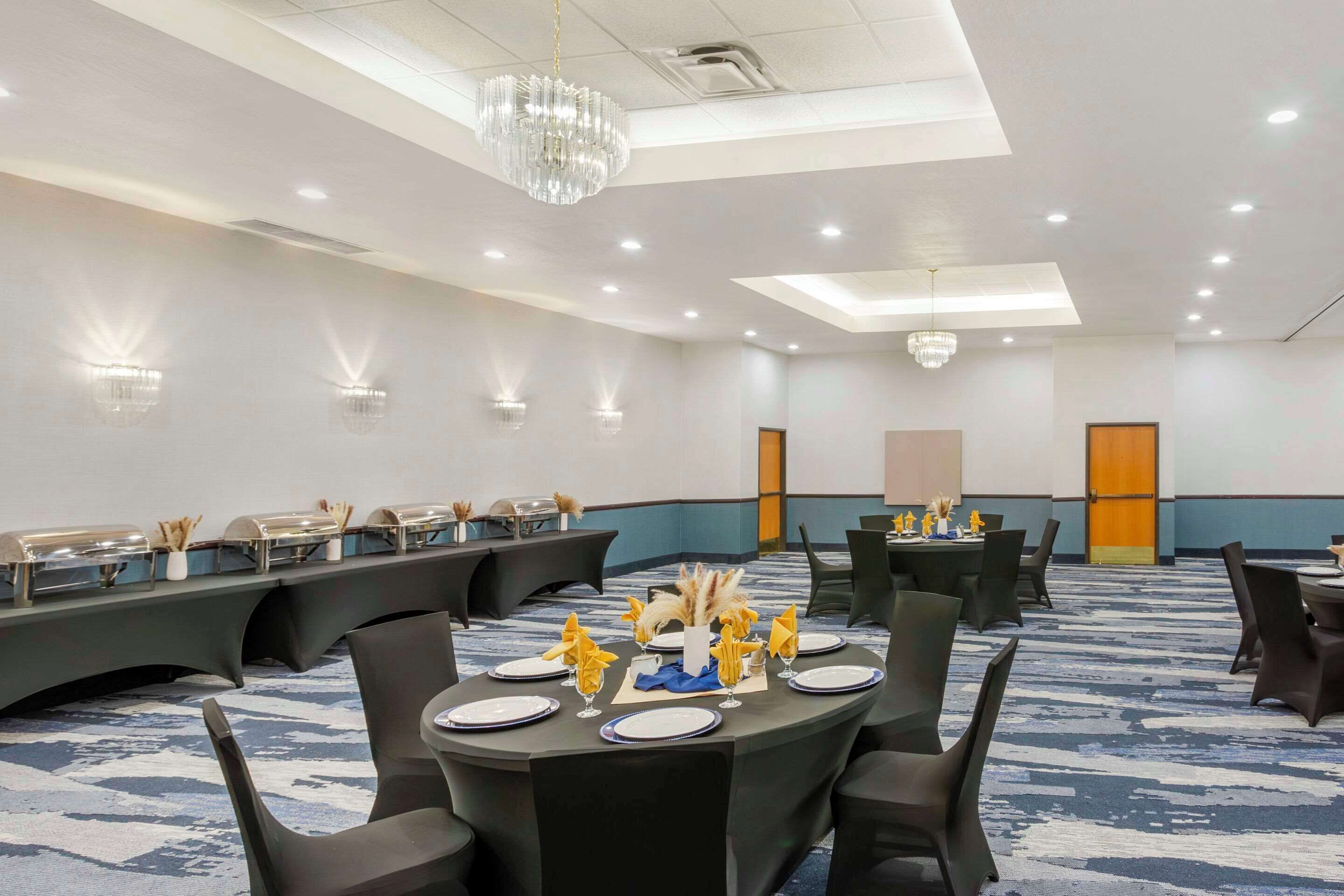 A conference room with round tables, chairs, and a carpeted floor.
