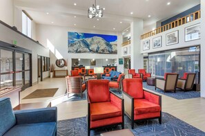 A spacious lobby with a high ceiling, a large wall mural of mountains, and a seating area with red and blue chairs. - Comfort Suites Ogden Conference Center (Ogden)