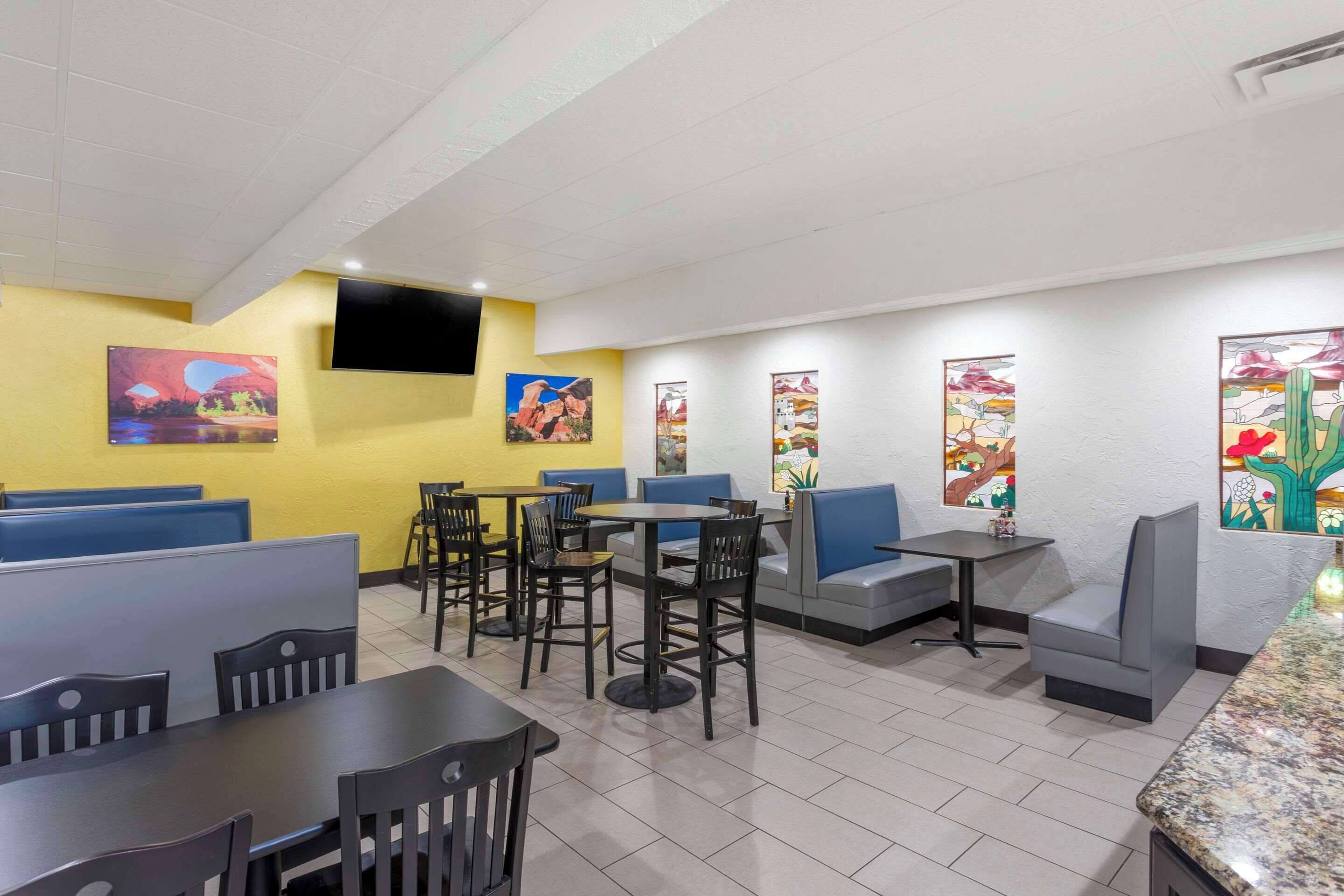 A restaurant with booths, tables, and chairs. There are paintings on the walls.