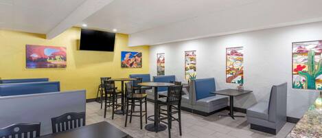 A restaurant with booths, tables, and chairs. There are paintings on the walls.
