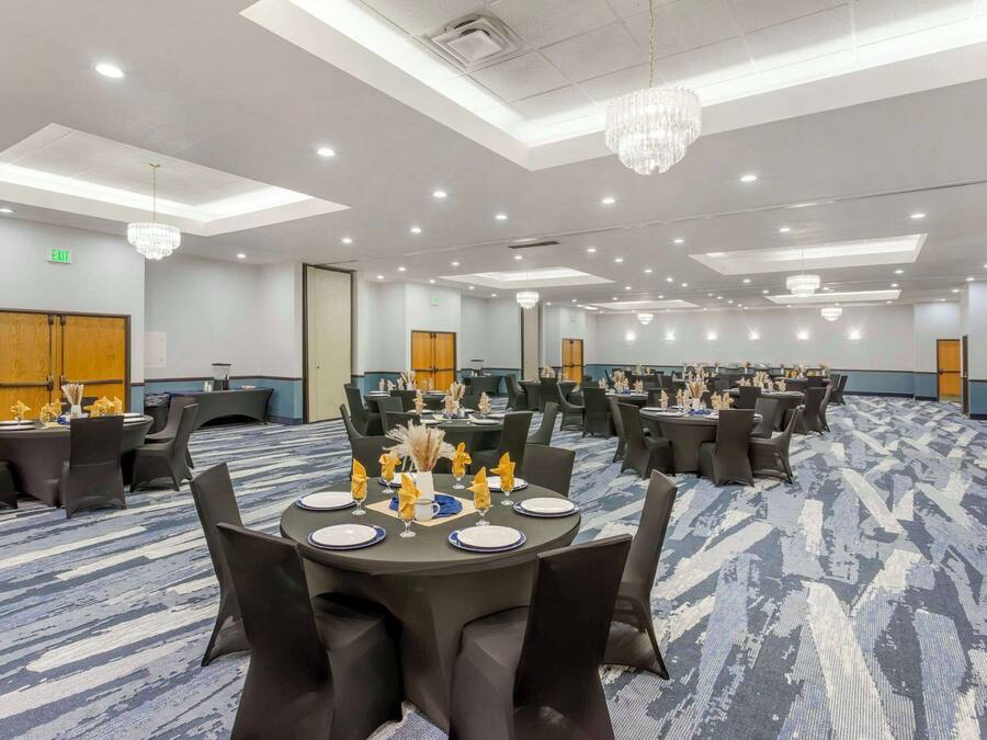 Un salón de conferencias con mesas redondas, sillas negras y candelabros.